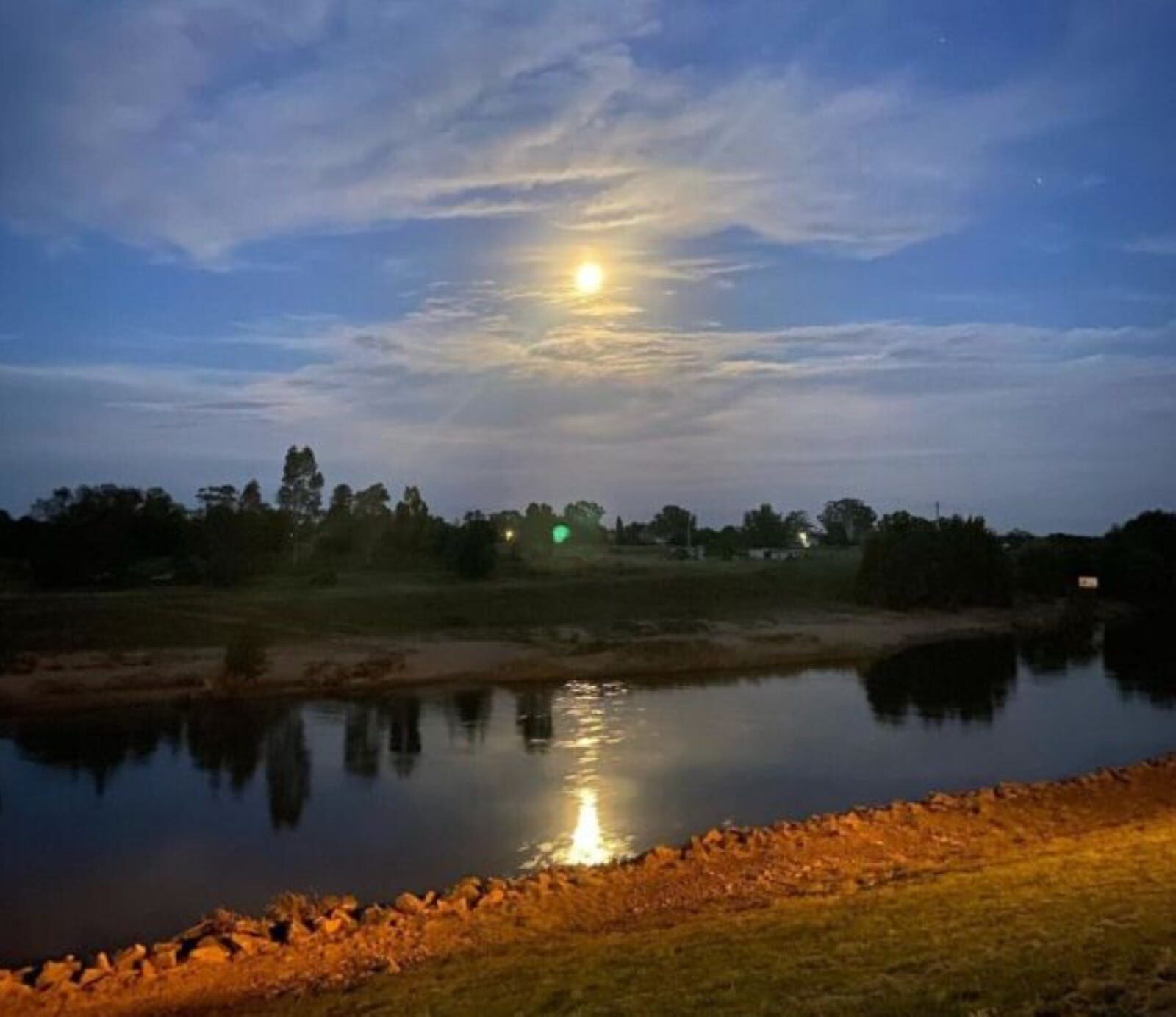A river with a body of water and a moon in the sky