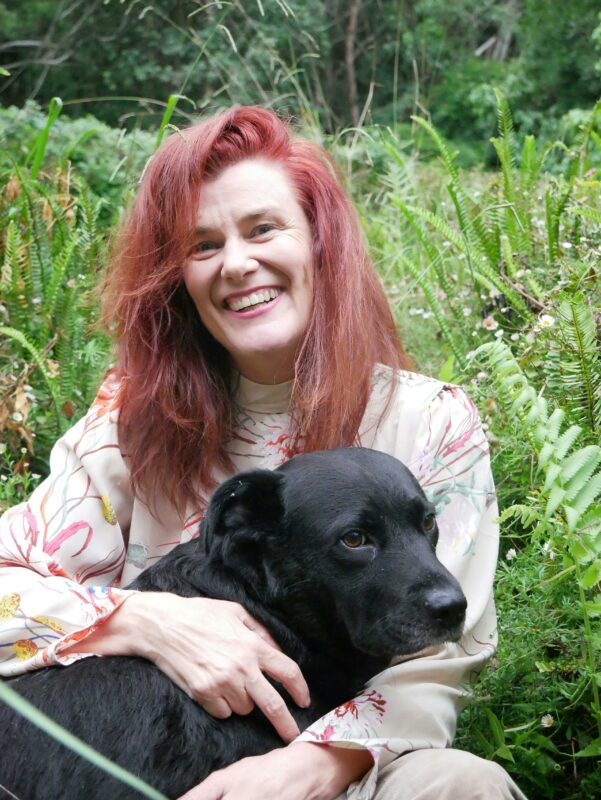 Lady with long red hair holding her black dog