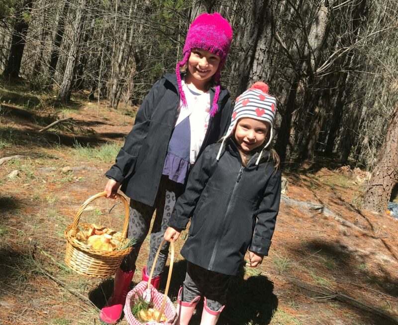 two kids with baskets full of mushrooms in a forest