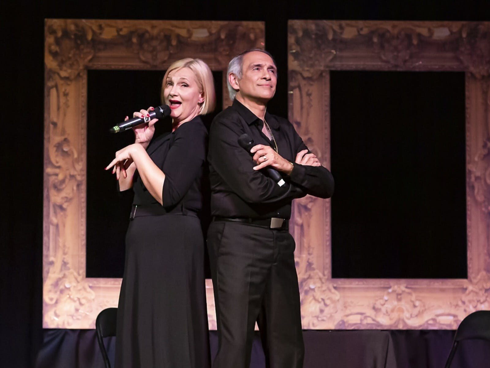 Two performers on stage mid performance looking into the distance wearing black garments