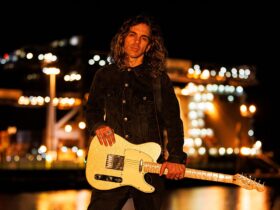 Nathan Cavaleri holding a gold guitar in front of lights