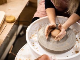 Photo of hands around a ball of clay on the pottery wheel