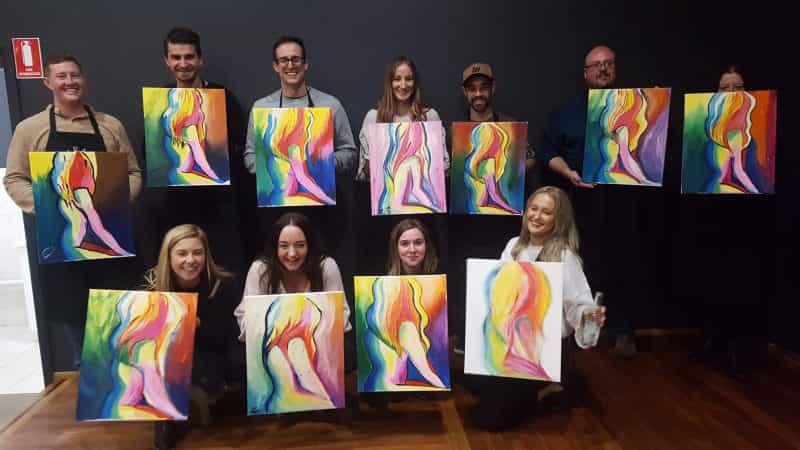 Group sharing their completed paintings from our Paint and Sip experience.