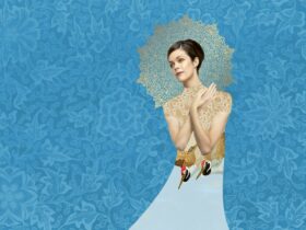 A beautiful woman wearing a white dress, with birds on it, standing against a blue floral background