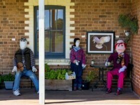 Three scarecrows on a verandah representing an artist, a woodworker and a photographer