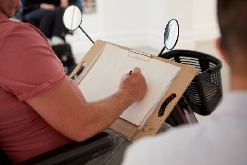 Motorised scooter user sketching an artwork on a clipboard