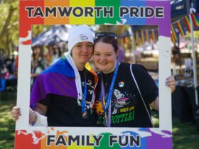 The image shows two young people with pride colours on holding a tamworth pride sign