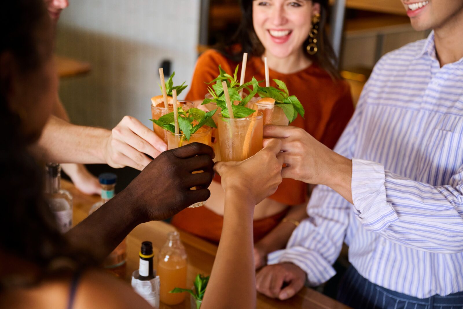 Group of people cheers their newly made orange cocktails