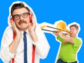 A man with glasses and suspenders covering his ears while a man plays a toy trombone.