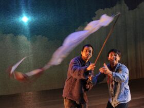 Two men on stage waving a white flag.