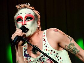 Artist singing into a microphone, they have dramatic make up on