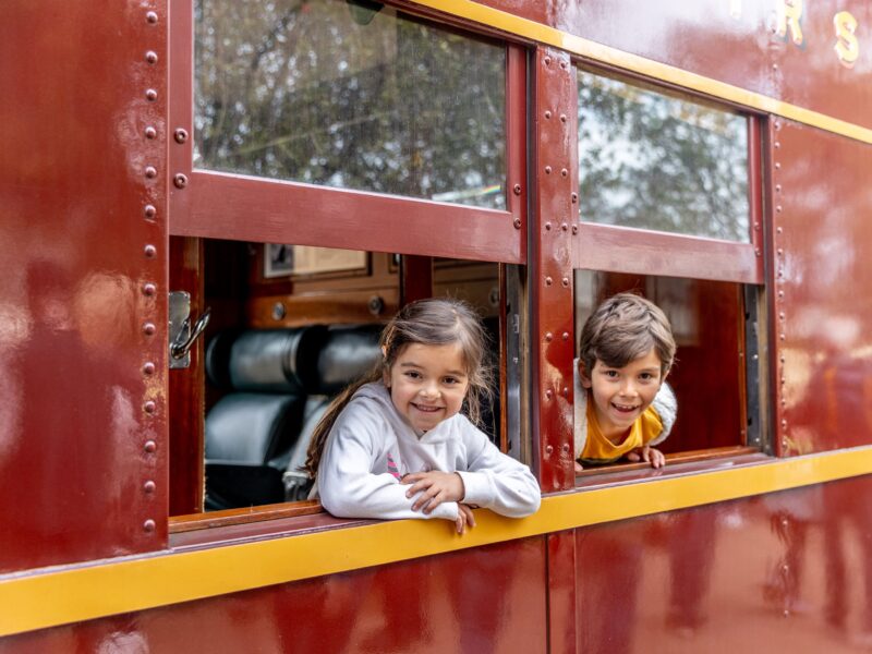 Kids smiling out the window of a steam train