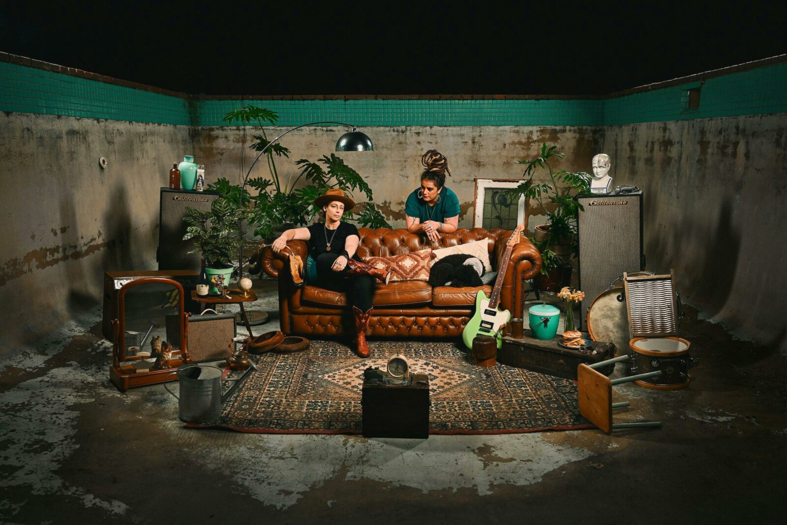 Members of the band This Way North, sitting on a brown couch in a dirty room, with a small tv.