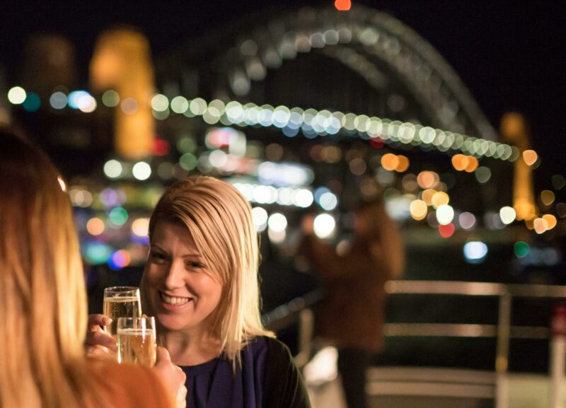 Two girl friends toasting champagne in front of Harbour Bridge