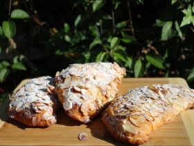 3 delicious almond croissants on a timber chopping