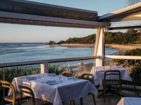 Outdoor dining overlooking beach at dusk. Tables set with white table clothes.