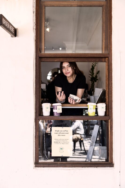 Female in window of cafe, order here sign above