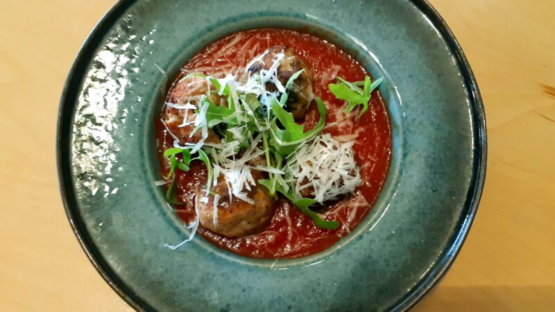 Pork and goat cheese meatballs in a tomato sauce in bowl on table