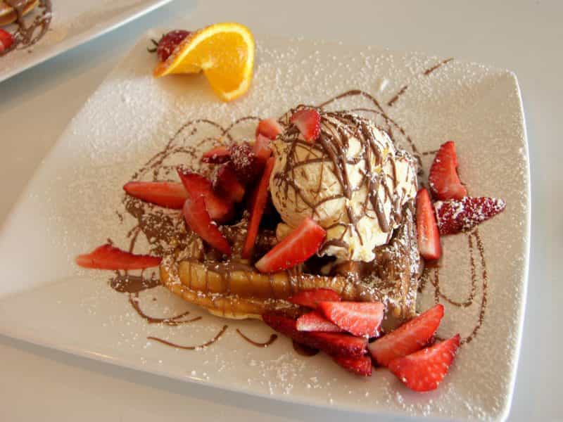 Waffles drizzled with belgian chocolate served with ice cream and strawberries