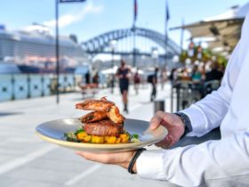Eastbank Cafe's surf and turf held by a waiter in the alfresco dining area overlooking the Harbour