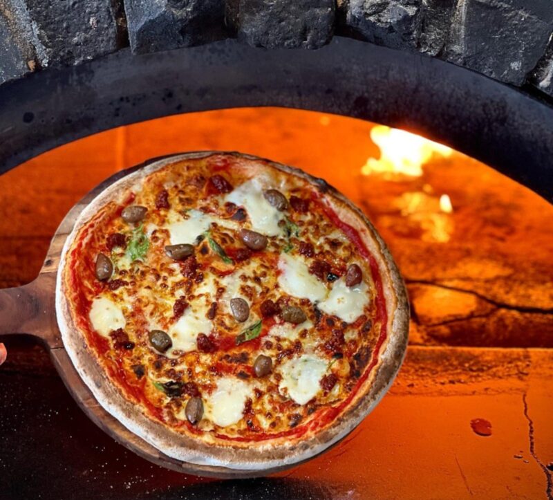 a pizza coming out of a pizza oven