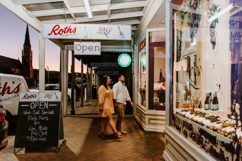 Couple enter Roth's Wine Bar from street at sunset backdropped by church steeple