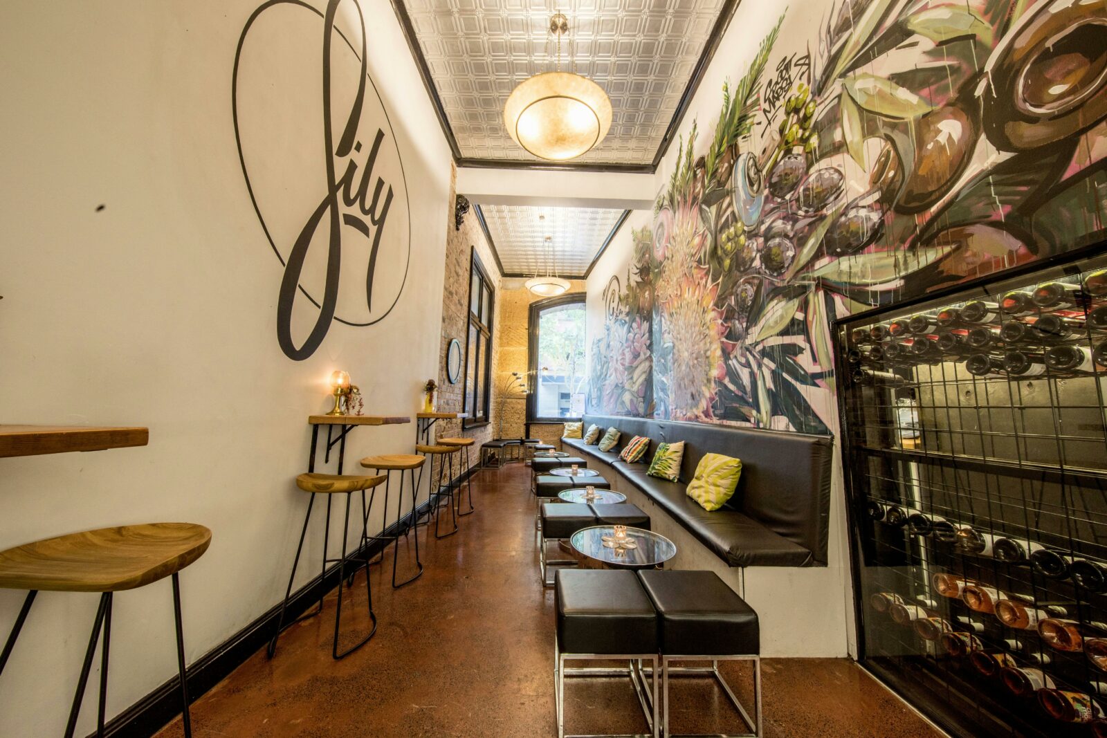 A narrow indoor seating area with colorful murals on each wall,
