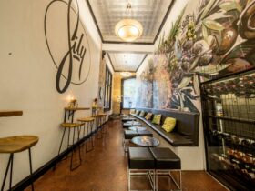 A narrow indoor seating area with colorful murals on each wall,