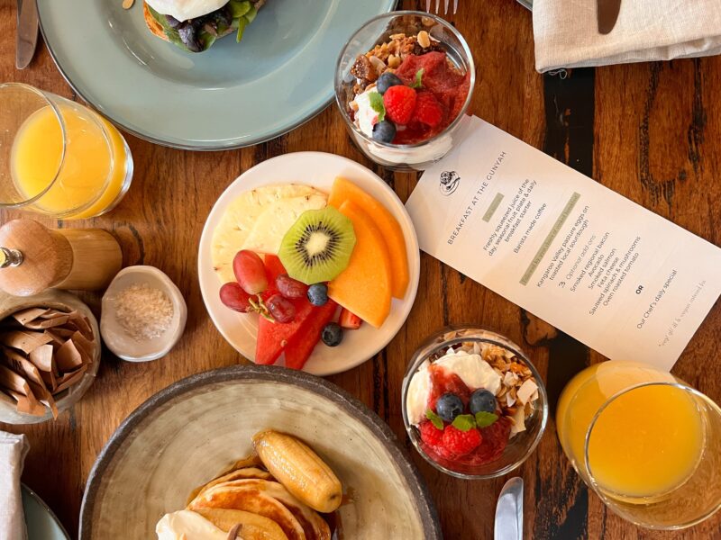 laden breakfast table with fruit granola and pancakes