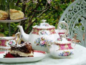 China tea service with cakes and scones on an outdoor table with a tablecloth