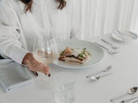 woman sitting at a table, holding a glass of wine beside her degustation menu item