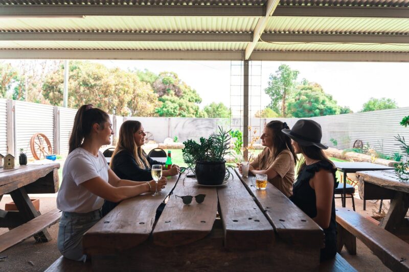 4 girls sitting around a big table in a garden