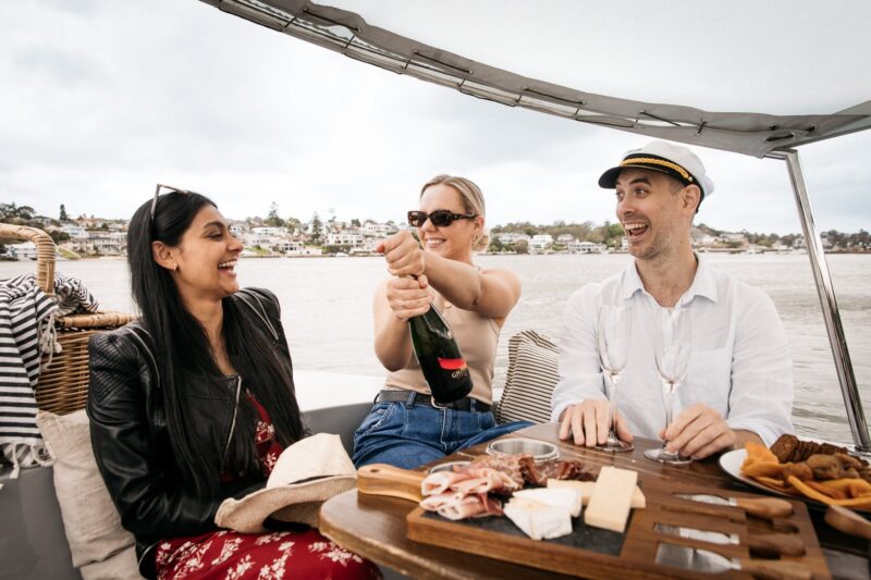 Three people sit on a GoBoat with a bottle of champagne