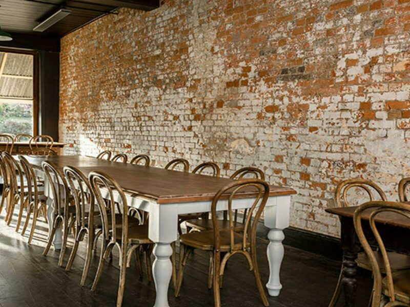 Tables and chairs inside Hosies at Hill End Historic Site with an exposed brick wall in the