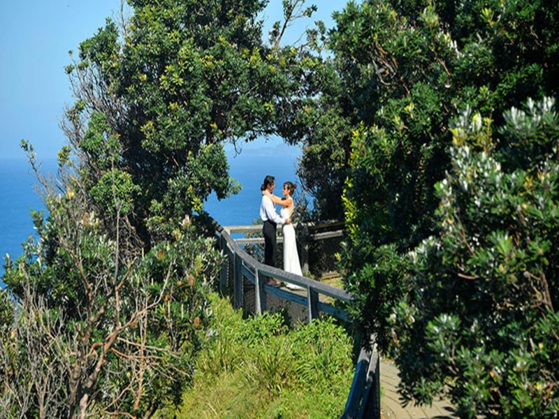 A couple standing under a natural arch created by trees at Most Easterly Point in Cape Byron State
