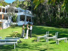 A couple and a celebrant saying their vows on Wategos lawn in Cape Byron State Conservation Area.