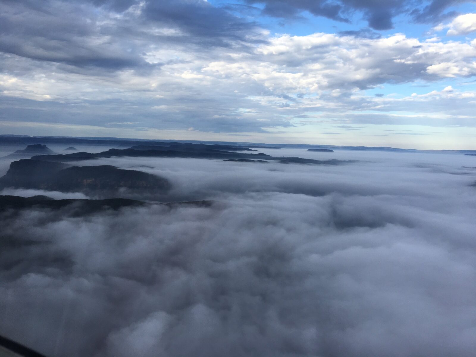 An aerial photograph of the Capertee Valley in the early morning, showing cliffs and low clouds.