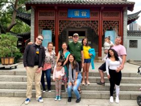 Teams of family smiling in front of Chinese garden gate