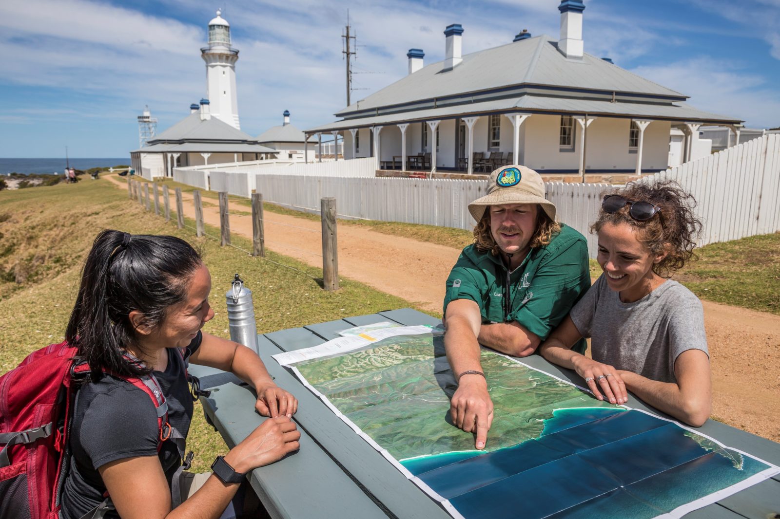 Guide showing guests places on a map while seated in the sun outside the heritage listed lighthouse