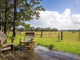 a deck with 2 chairs over looking pasture land