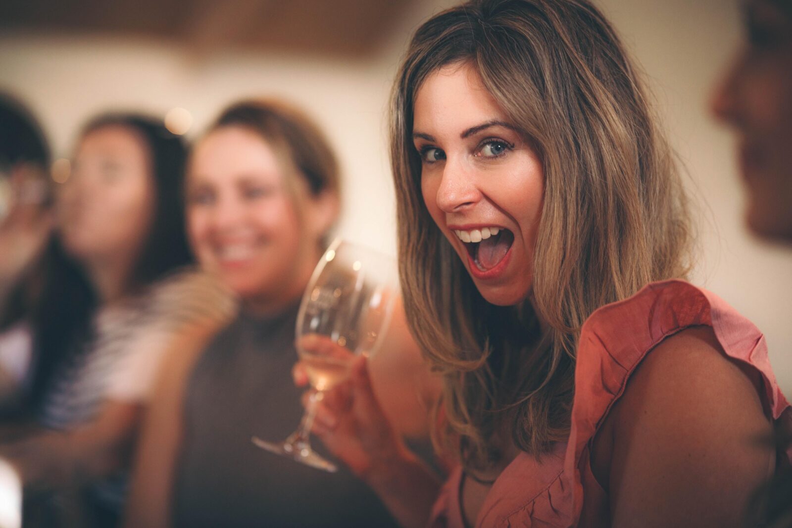 A lady holding a wine glass smiling at the camera