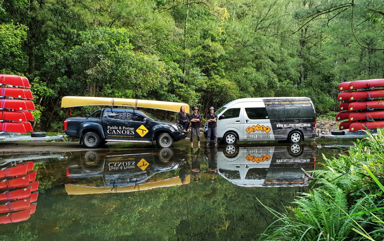 two vehicle with canoes reflecting in the water