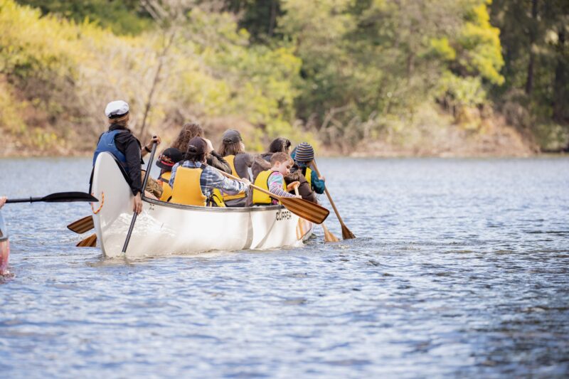 a large canoe with 14 people paddling away