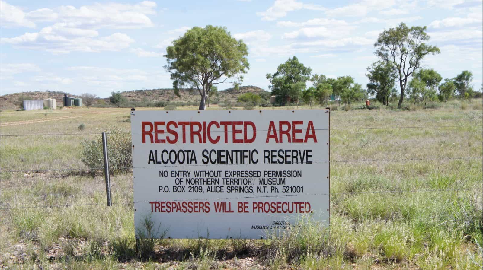Sign at entry gate into the Alcoota Fossil Beds researchers field camp site, which can be seen in the background.