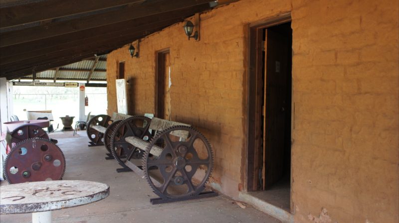 Verandah area of mud hut, with display of machinery parts