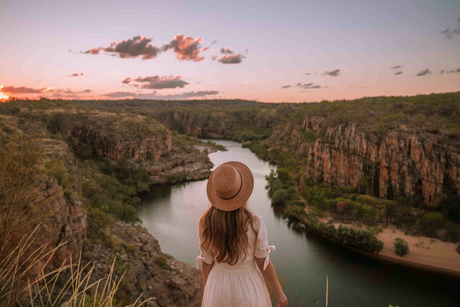 Girl standing on the edge of a weaving escarpment in Katherine Gorge at sunset