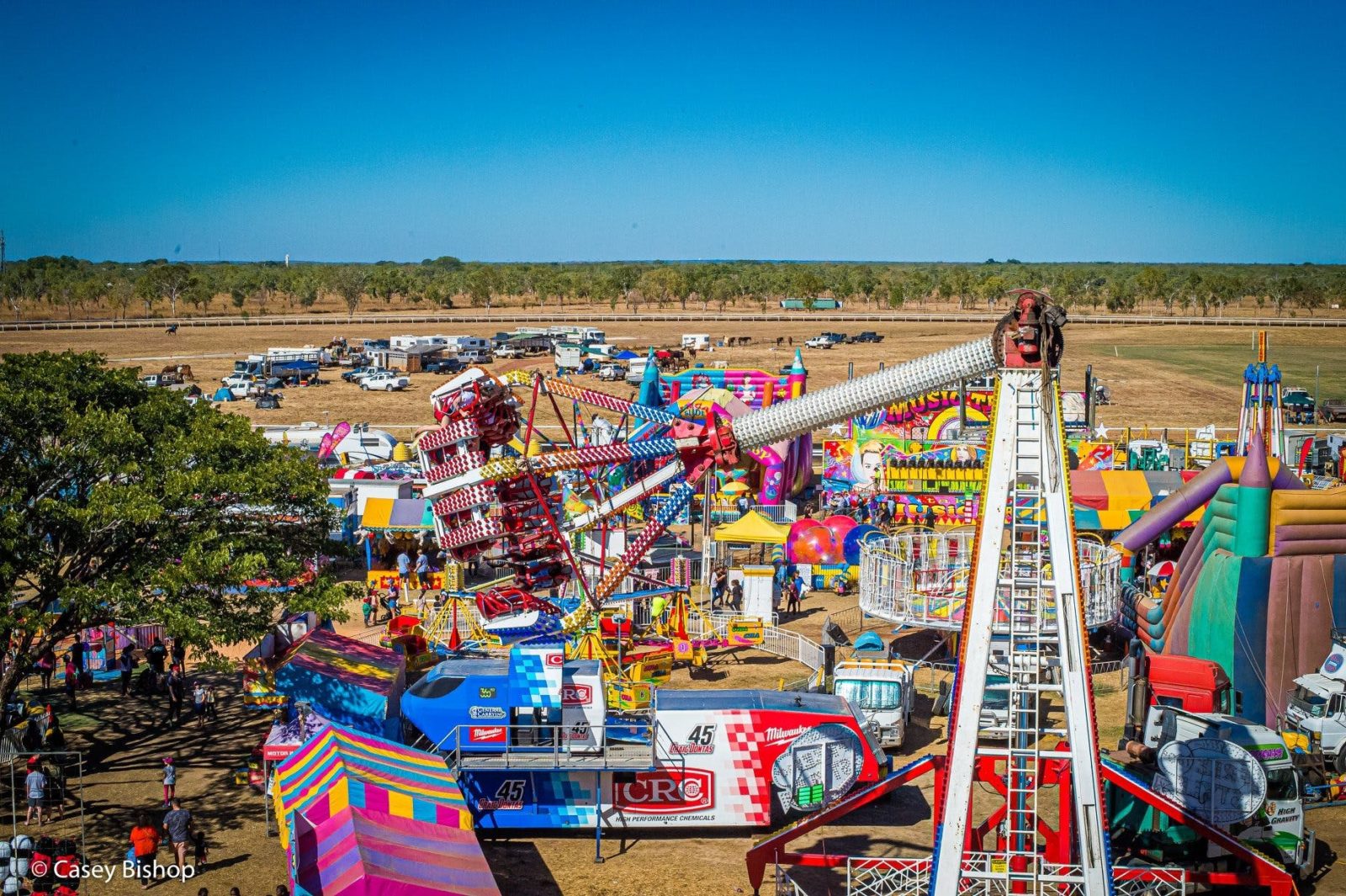 Photo of show amusement rides against backdrop of rodeo arena and rural landscape