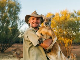 Chris Barns ('Brolga'), aka Kangaroo Dundee, cuddling a red kangaroo.