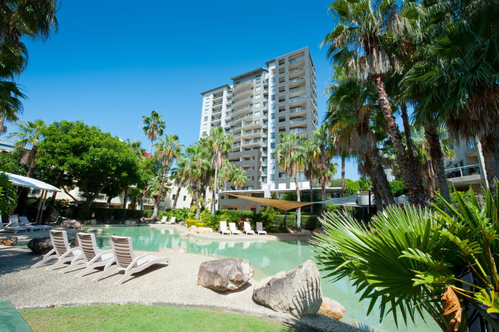 View of lagoon style pool with apartment building behind.