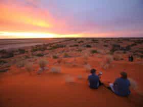 Visitors enjoying Diamantina's red sand hills and sunset.